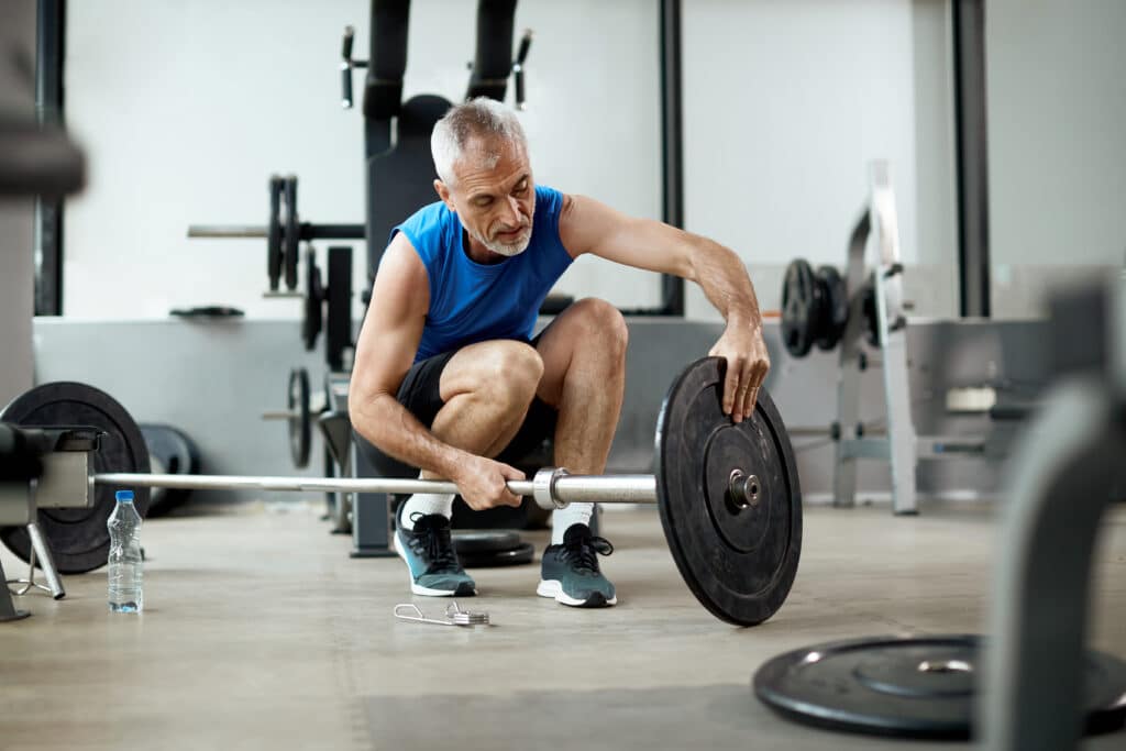How Hard Should I Exercise: Image of an Older Man Preparing to lift weights with a barbell