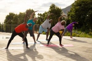 Multiracial seniors exercising on mats over hardwood floor against plants in yard