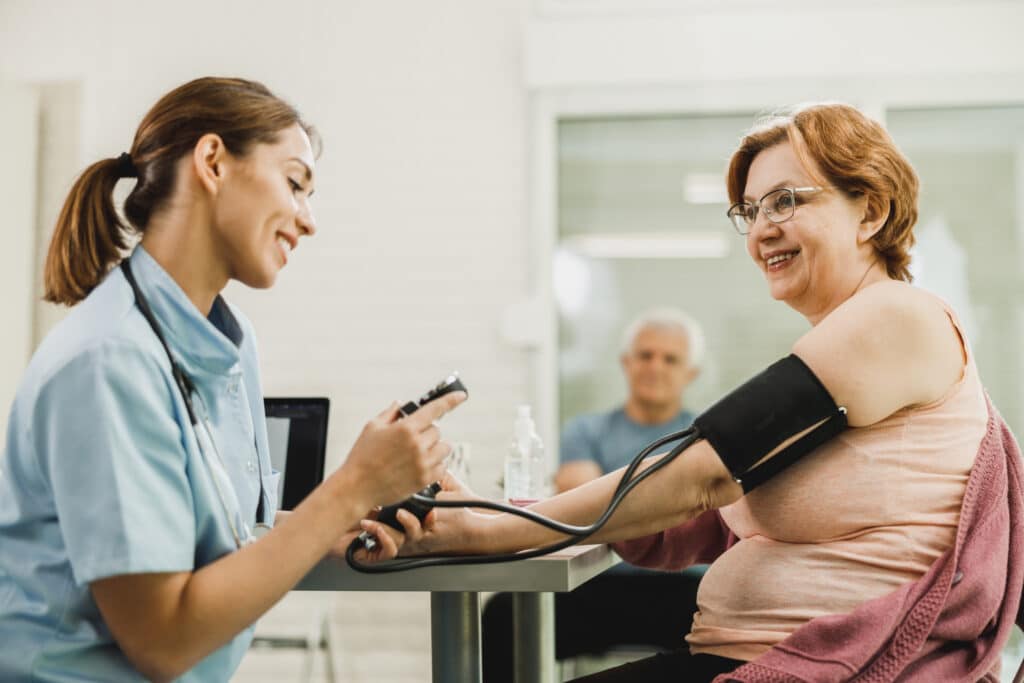 A smiling older woman has her blood pressure measured after exercise.
