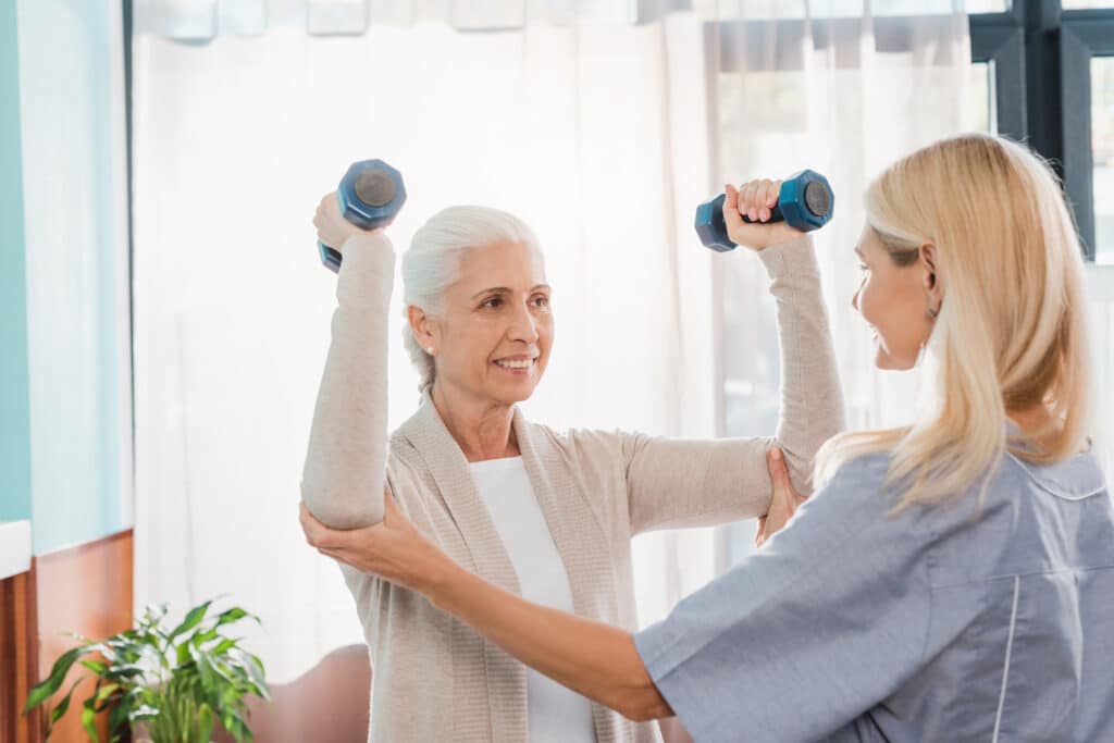 Menopause and joint pain: a smiling senior woman gets physical therapy from a female PT