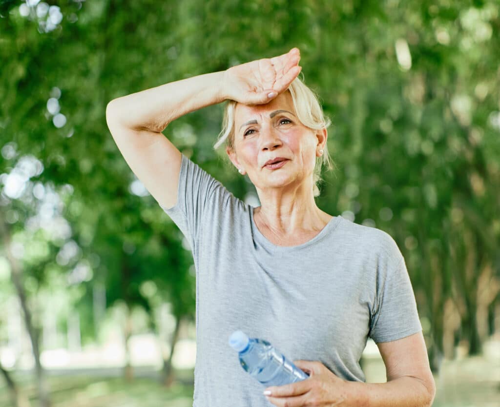 Dealing with the heat: an older woman recognizes the signs of heatstroke outdoors.