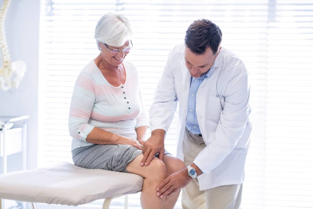 A senior woman has her knee examined while considering proper supplements for joint health