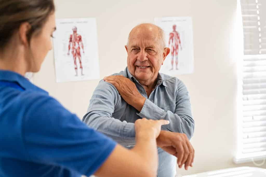 Pinched Nerve in the shoulder: image of an older man talking to his doctor about shoulder pain