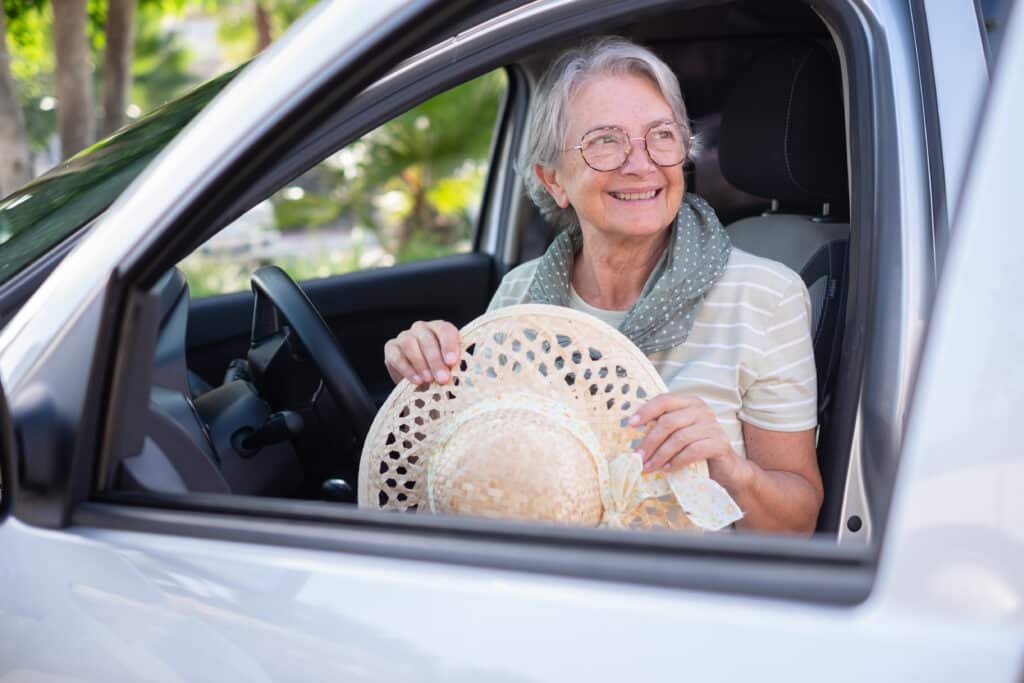 Driving without pain: a senior woman happily sits in the driver's seat