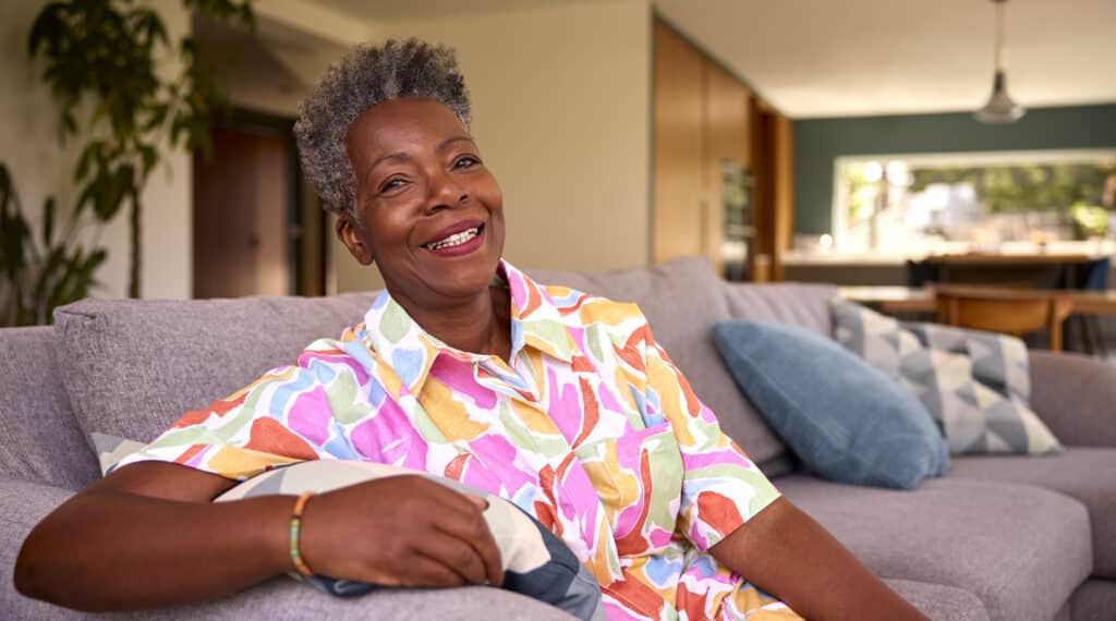 Aging in place: a senior African American woman relaxes on her couch.
