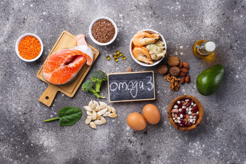 Supplements for joint health: Omega 3 fatty acid sources including fish and seeds on a slate gray surface