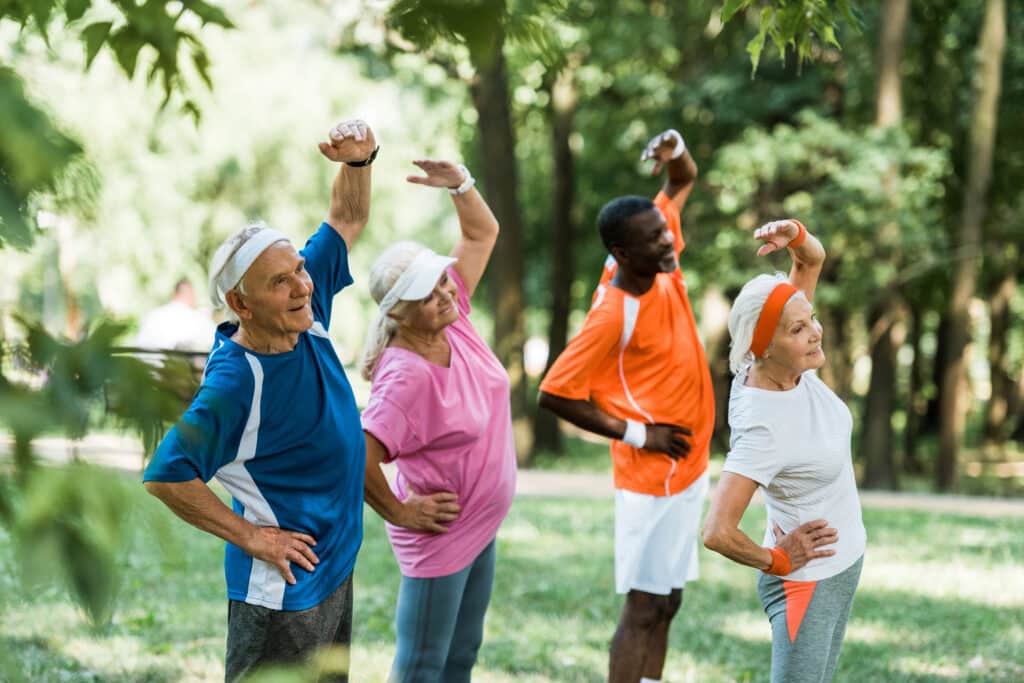 Group of senior exercisers stretching in the park
