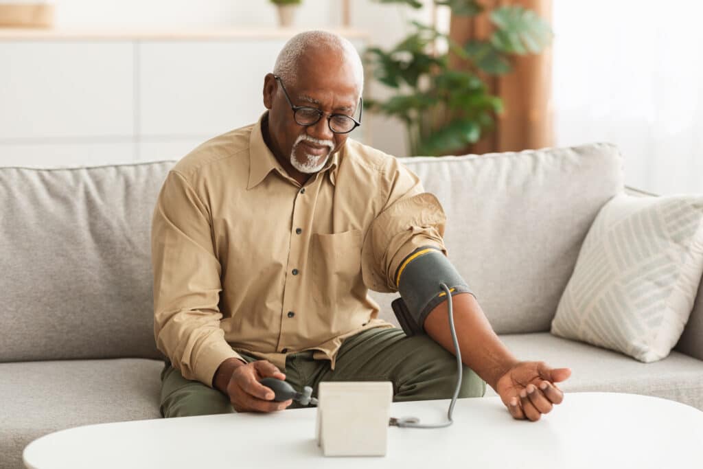 Older African American man reads his blood pressure readings at home