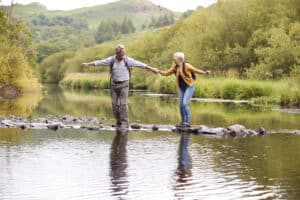 Backward disequilibrium: a senior couple crosses a creek while hiking