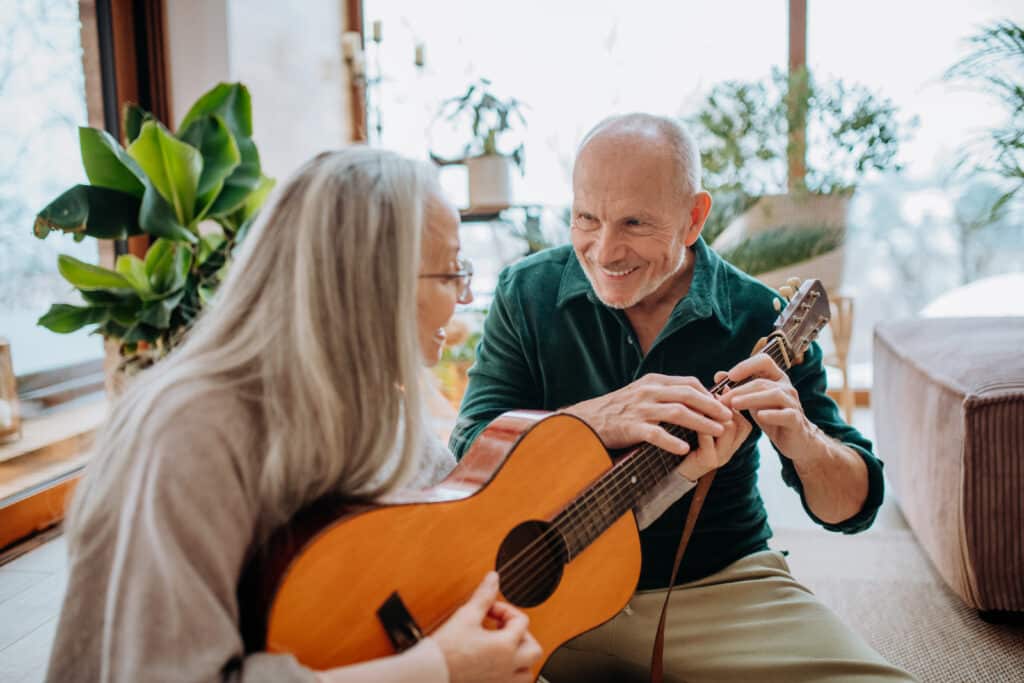 A senior woman learns guitar from her friend
