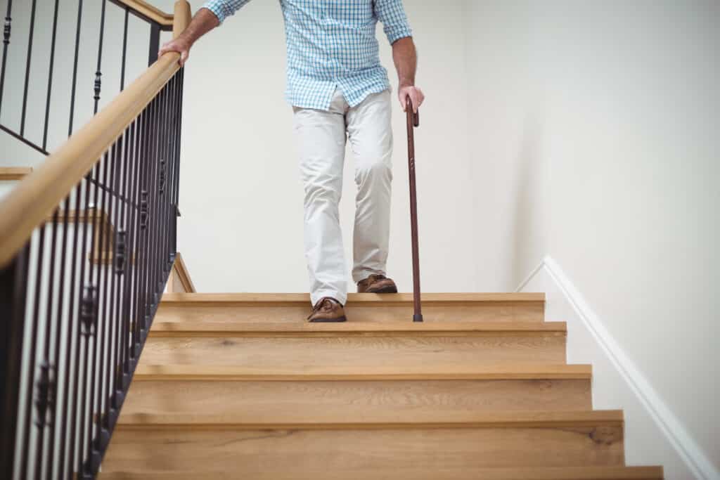 a senior using a cane while walking down a flight of stairs.