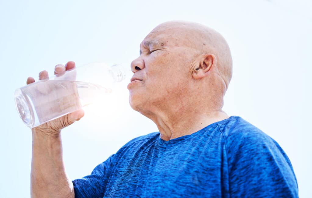 A senior man drinking water to stay hydrated