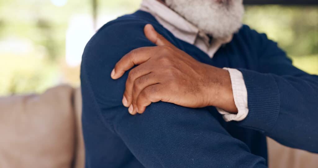 Exercises for frozen shoulder: image of an older man rubbing an achy shoulder