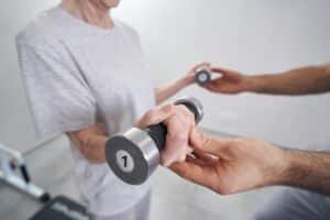 Senior person training arm musles with hand weights