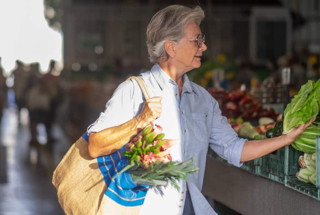 The SAID principle: A senior woman holds a heavy grocery bag while she shops