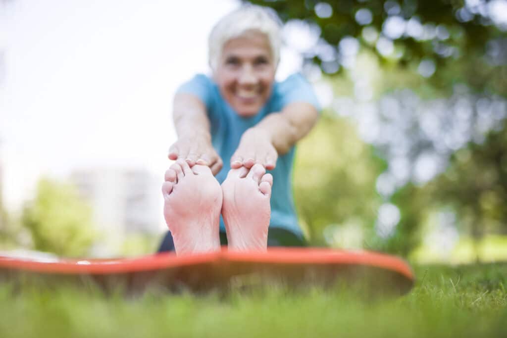 Image of a woman stretching barefoot outdoors in the park