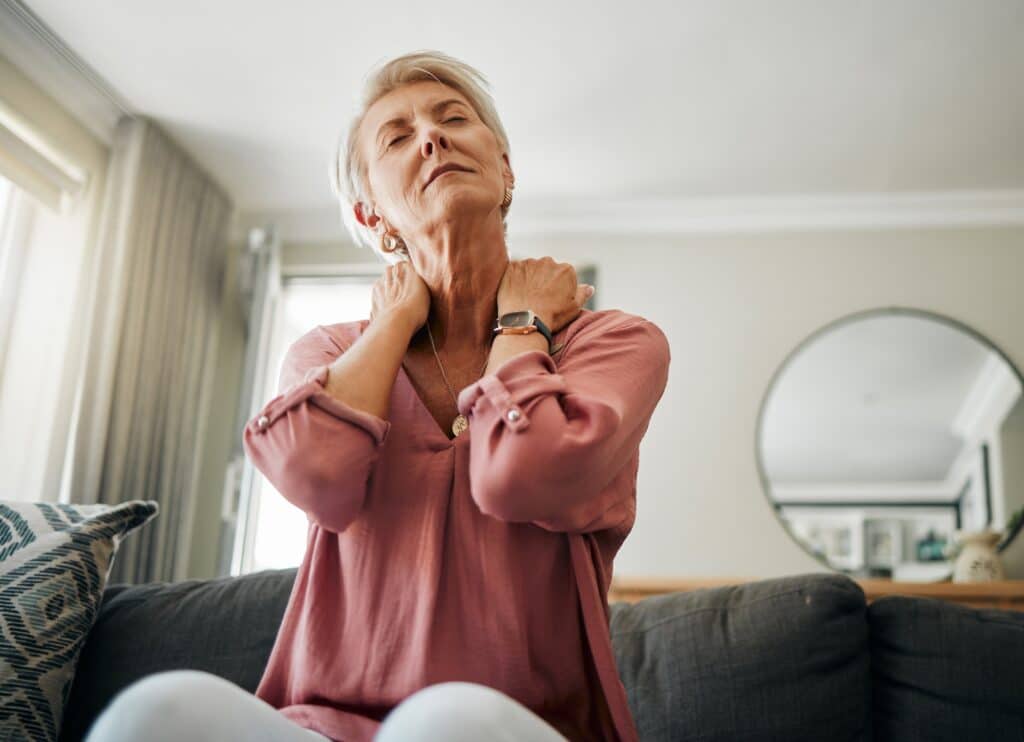 Senior woman, neck pain and stress in living room home of spine injury, fibromyalgia and osteoporos