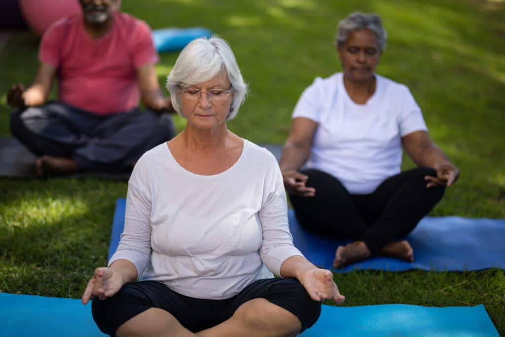 Seniors meditating at the park for stress reduction