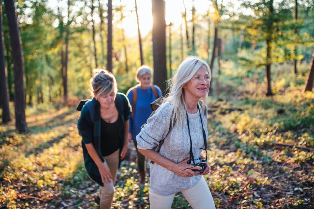 Three active older women hiking and taking photos together