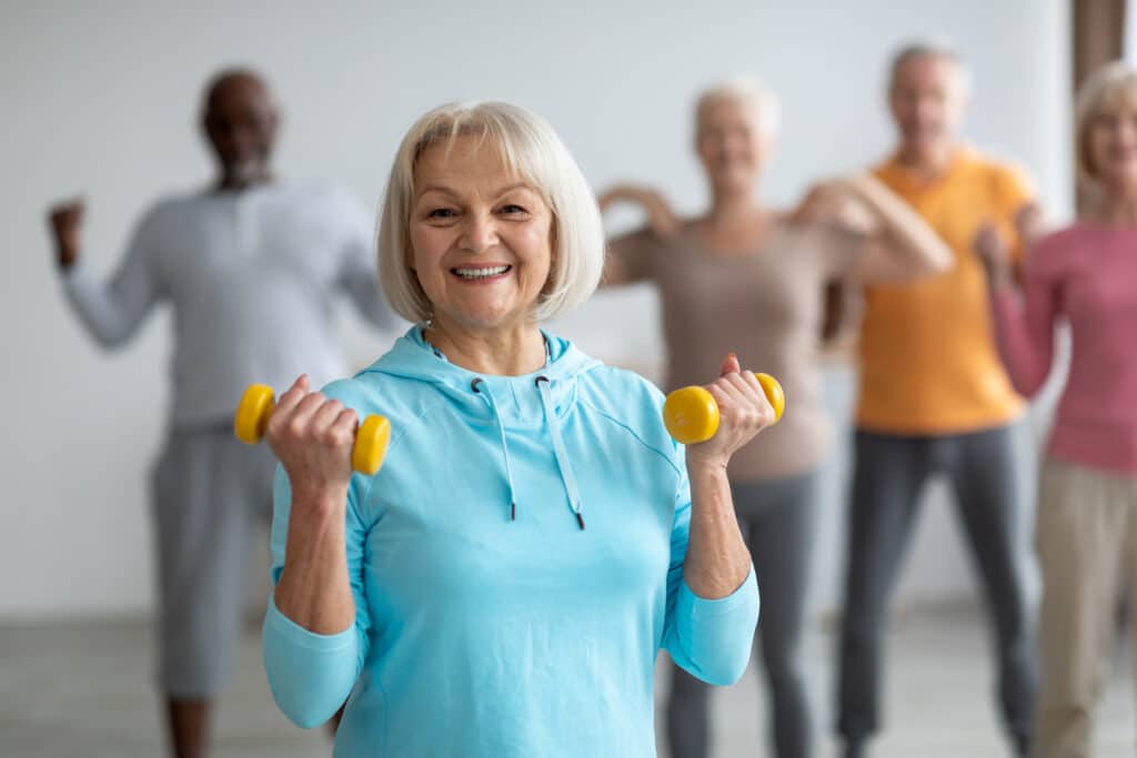 Stretching vs strengthening: a group of seniors lift weights and exercise in a fitness class