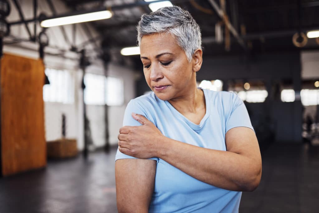 Senior woman encountering shoulder pain at the gym
