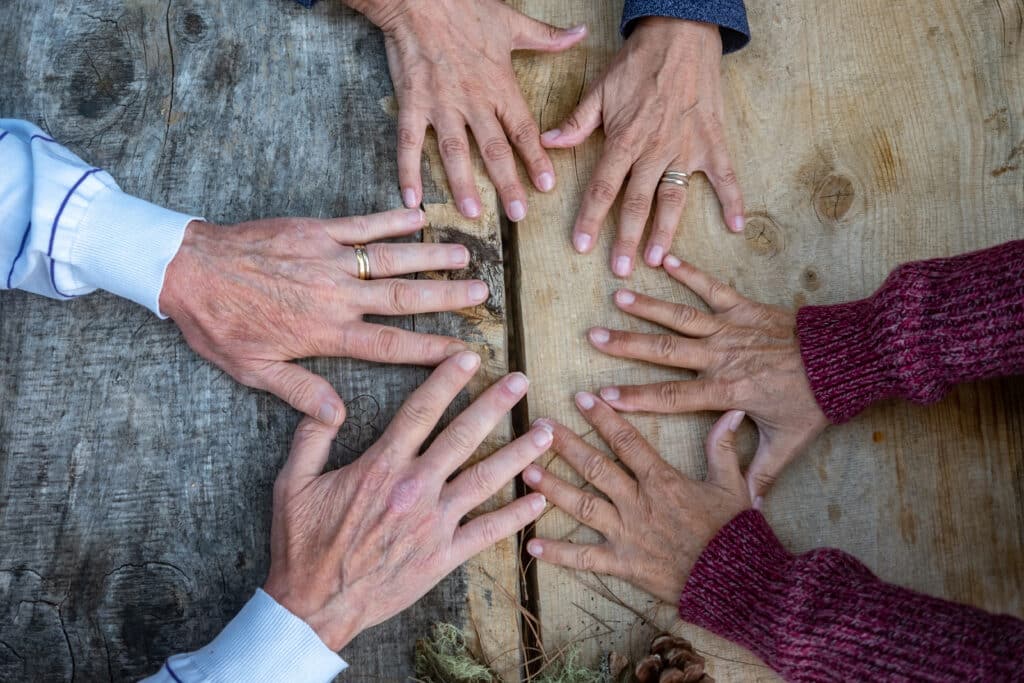 Image of five seniors' hands on a table surface