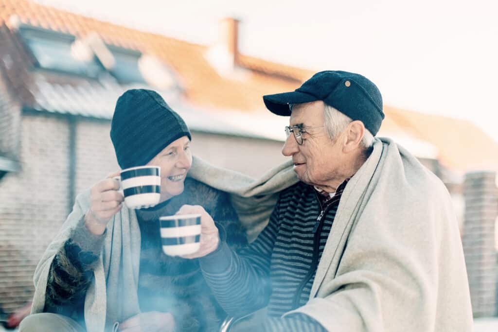 A senior couple enjoying coffee outdoors in the winter time.
