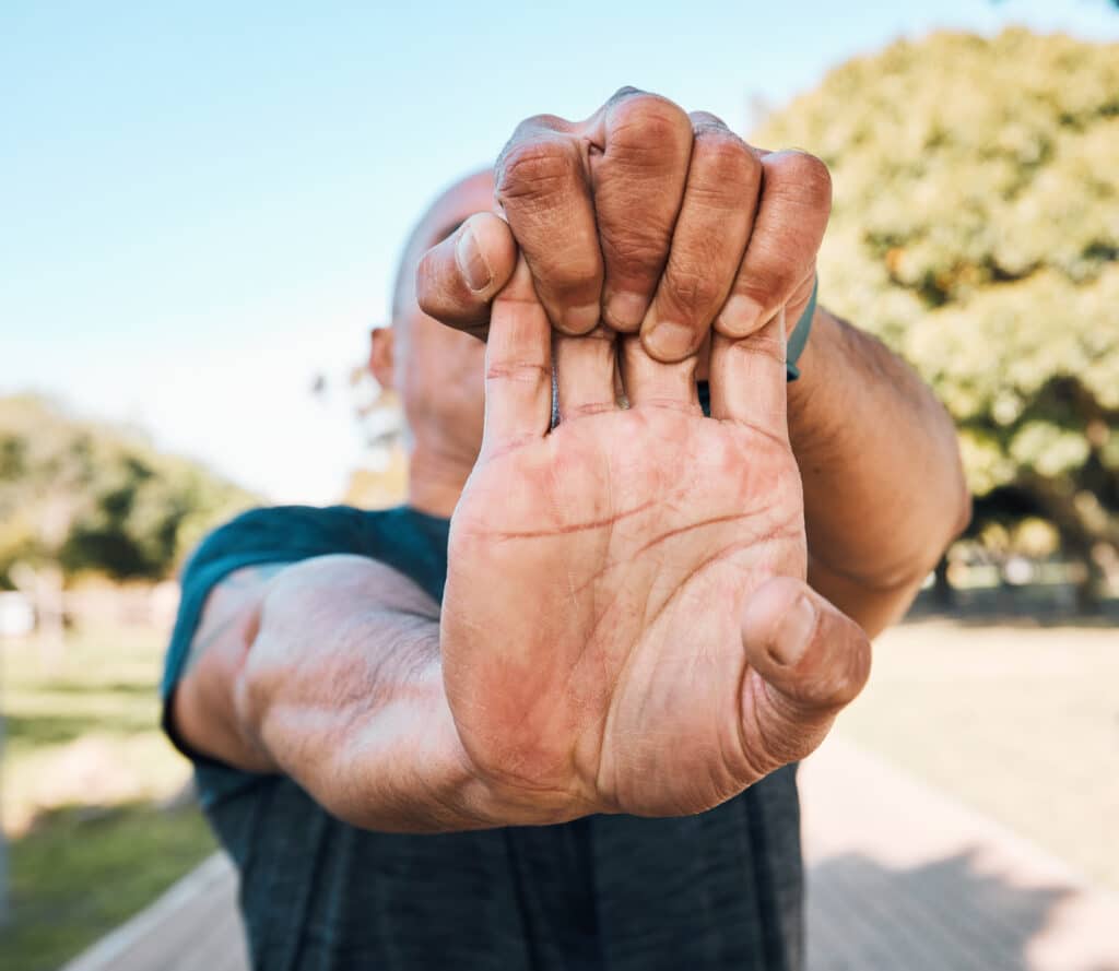 A man stretches his hands outdoors to prepare for exercise