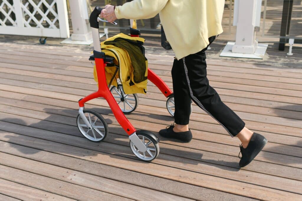 A senior woman briskly walks with her red rollator walker