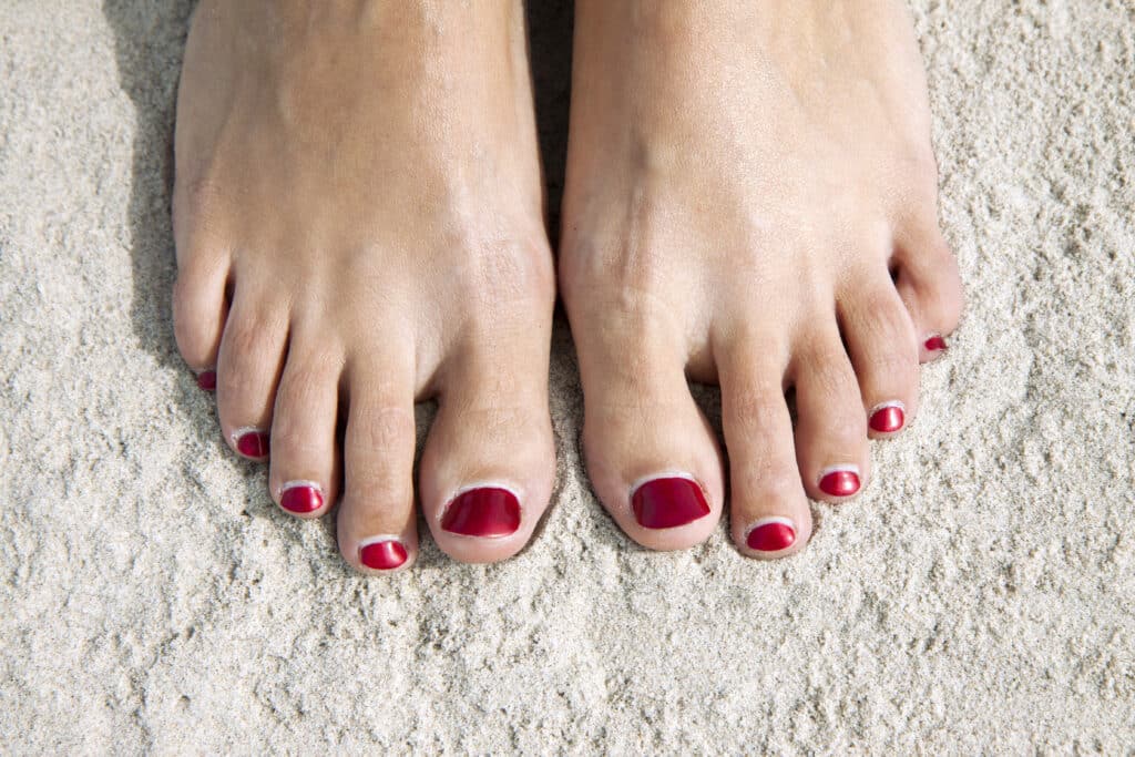 Image of a woman's painted toenails at the beach