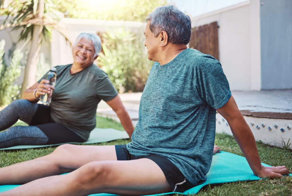 Image of a senior Hispanic couple  laughing while they rest after a yoga class.