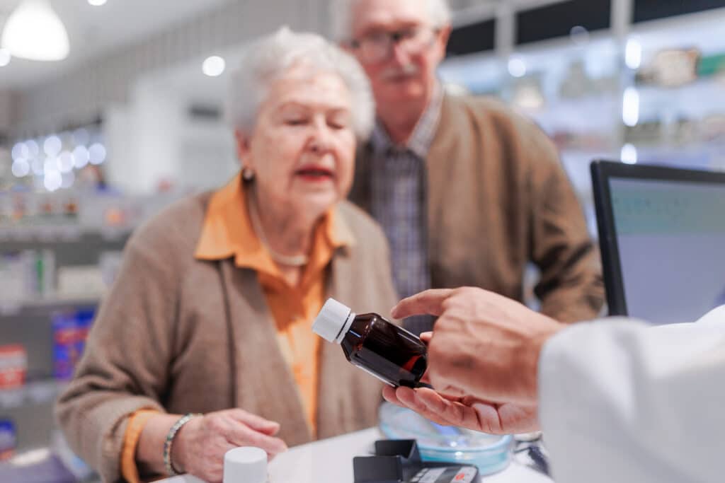 An older couple asks a pharmacist about medication and heat interaction